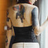 Person with tattoos on their back and arms, wearing a black top.